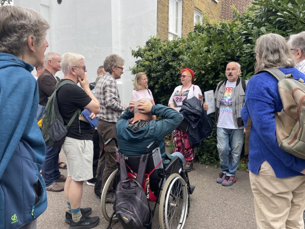 Colour photograph showing people on a local history walk, including the two guides and a person in a wheelchair